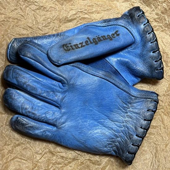 Pair of blue motorcycle gloves stacked on a wooden table.