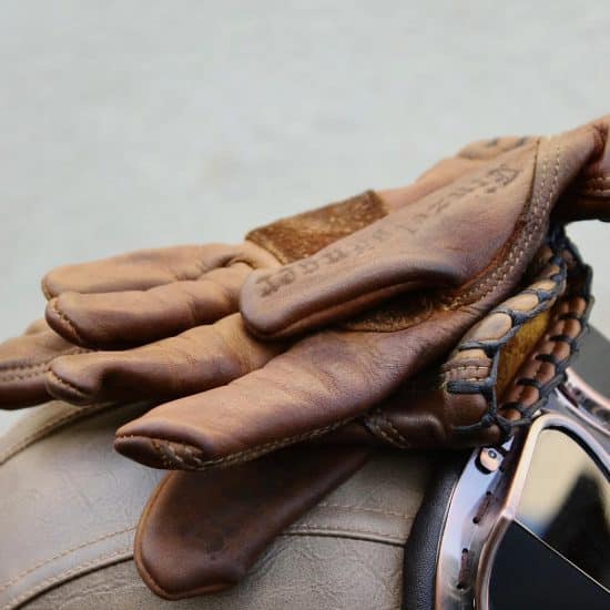 Vintage dark oak motorcycle gloves stacked on a motorcycle.