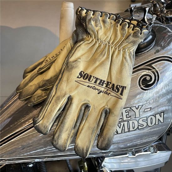 Bone white vintage motorcycle gloves stacked on a Harley-Davidson motorcycle.